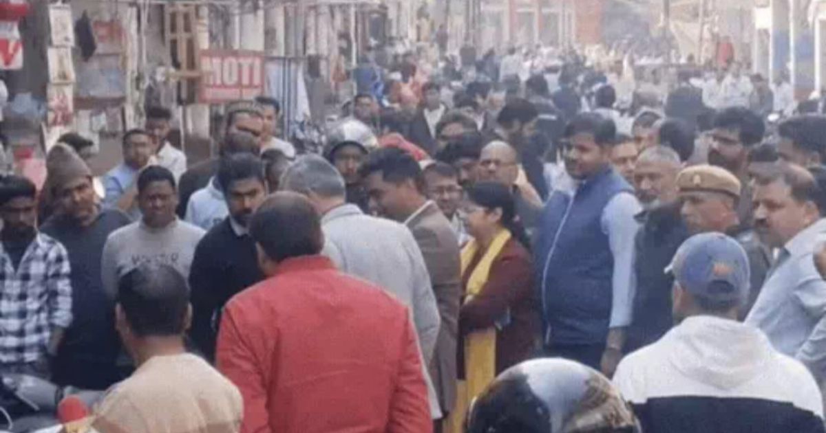 Agra News: फीता लेकर नाप-जोख करते अधिकारी, आसपास दुकानदारों की भीड़।